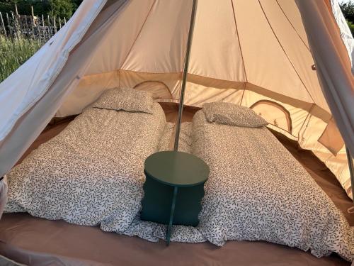 a tent with two beds and a green table in it at Tente Cocoon in La Brillanne