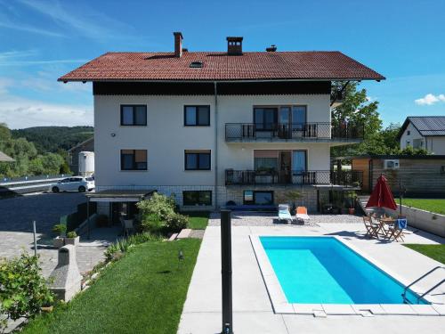a villa with a swimming pool in front of a house at Apartments Bukor with seasonal pool in Lukovica pri Domžalah