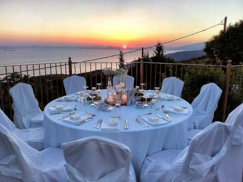 a table with white tables and chairs with the sunset at Lagou Raxi Country Hotel in Lafkos