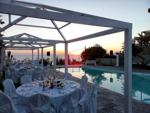 a marquee with white tables and chairs next to a swimming pool at Lagou Raxi Country Hotel in Lafkos