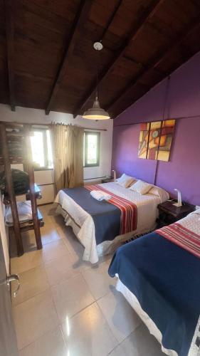 a bedroom with two beds and a purple wall at Descanso de las Piedras in Tafí del Valle