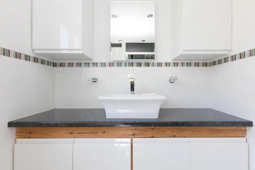 a white bathroom with a sink and a mirror at Ocean Parc in Carbis Bay