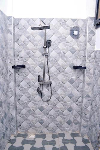 a shower in a bathroom with a tiled wall at Residence LaFina in Saly Portudal