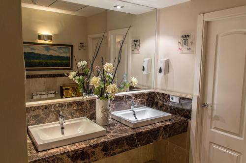 a bathroom with two sinks and a vase of flowers at Hotel Sevilla in Ronda