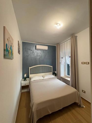 a bedroom with a white bed and a blue wall at ADA City Apartment in Palestrina