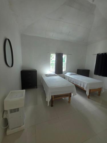 a white room with two beds and a tv at Ackee Haven Comfortable Spacious Home in Poor Mans Corner