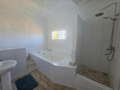 a white bathroom with a tub and a sink at Ackee Haven Comfortable Spacious Home in Poor Mans Corner