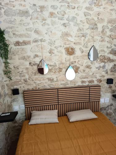 a bedroom with two pillows and a stone wall at Chambre du petit figuier in Aramon