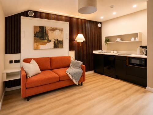 a living room with an orange couch and a kitchen at Westport Selfcatering Suites in Westport