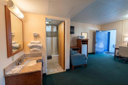 a hotel room with a bathroom with a sink and a chair at Travelers Inn by OYO Longview Kelso in Longview