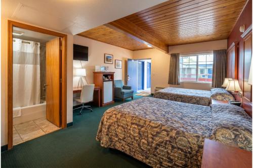 a hotel room with two beds and a desk at Travelers Inn by OYO Longview Kelso in Longview