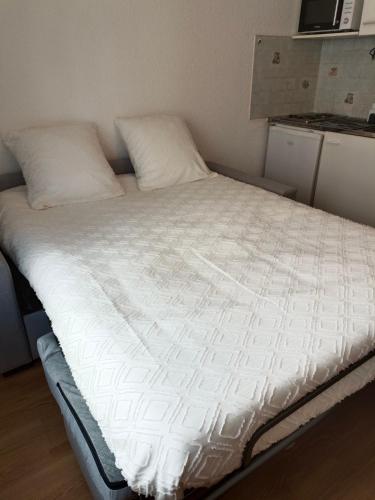 a bed with white sheets and pillows in a room at Studio PARAY CENTRE LOGIS 12 in Paray-le-Monial