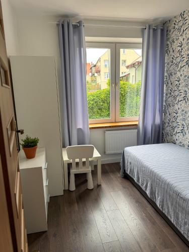 a small bedroom with a bed and a window at Apartament Flauta in Mikołajki