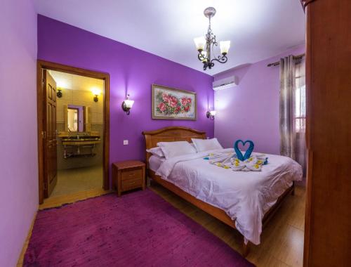 a purple bedroom with a bed with a purple wall at Blue Pearl Resort in La Gaulette