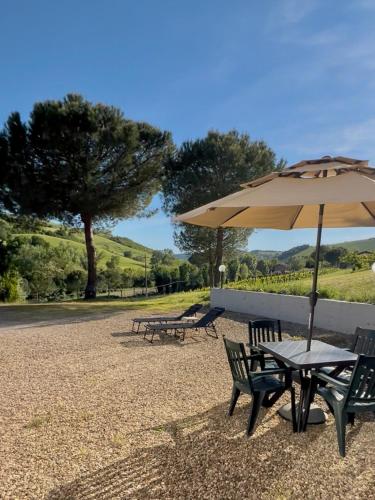 a picnic table with an umbrella and two benches at Dolce Collina, Sunset Terrace & Vineyard Views in Dozza