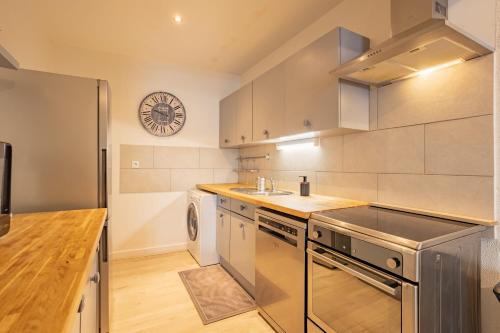 a kitchen with stainless steel appliances and a clock on the wall at Duplex hyper centre tout équipé - Arrivée autonome in Troyes