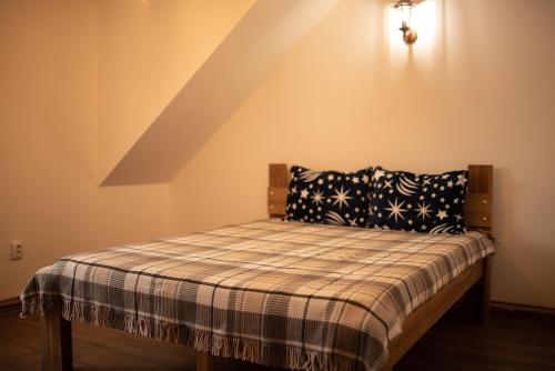 a bed with a plaid blanket and pillows in a room at Cabana La Urși in Ceraşul