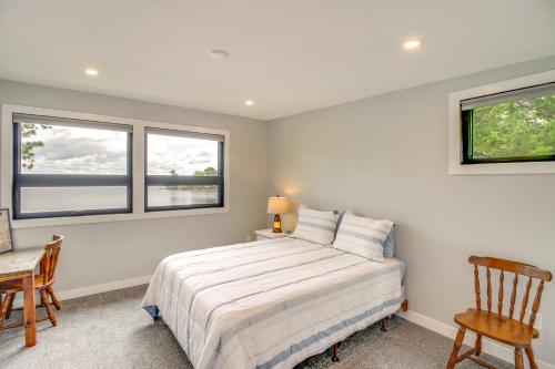 a bedroom with a bed and two chairs and two windows at Lakefront Northwoods Cabin w/ Shared Dock & Views! in Tower