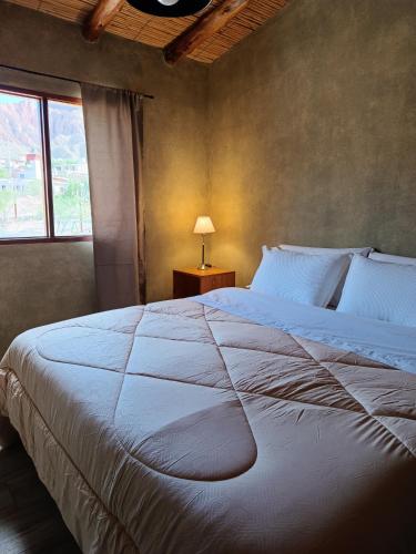 a bedroom with a large white bed and a window at Cabana Mirador Sumajpacha in Tilcara