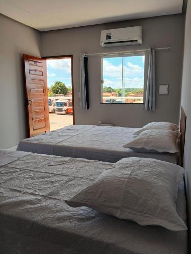 two beds in a bedroom with a window at Pousada Ômega in Caxias das Aldeias Altas