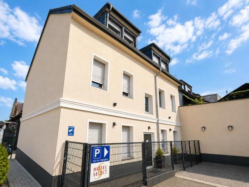 ein großes weißes Gebäude mit einem Parkplatzschild davor in der Unterkunft WOS Hotel in Mönchengladbach