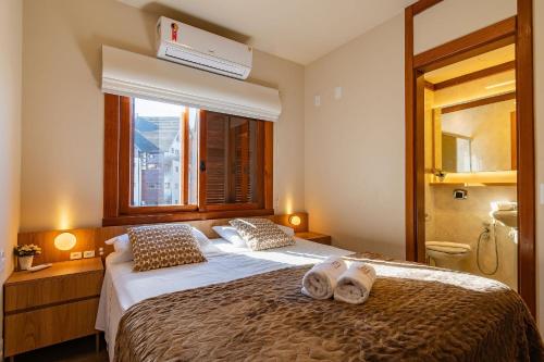 a bedroom with a large bed with towels on it at Rosa Condomínio Vale azul in Gramado