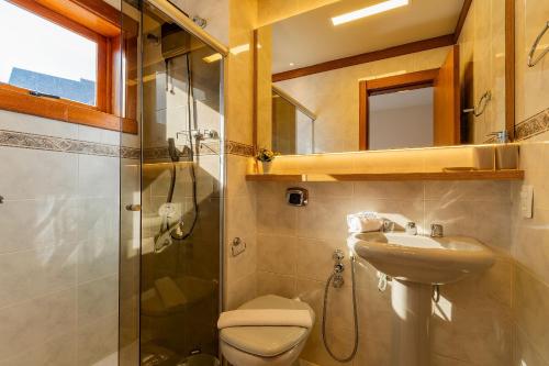 a bathroom with a toilet and a sink and a shower at Rosa Condomínio Vale azul in Gramado