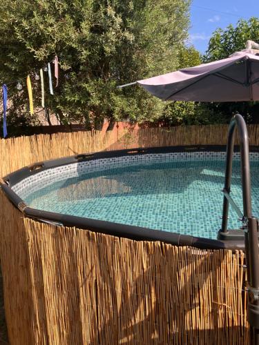 a swimming pool with an umbrella and a fence at Amis Wine House - Maison d'hôtes à 5 min de Saint-Émilion in Pomerol