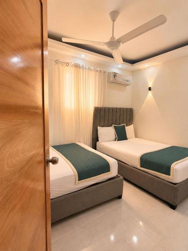 ein Schlafzimmer mit zwei Betten und einer Tür mit einer Decke in der Unterkunft Hotel Reloj in San Felipe de Puerto Plata