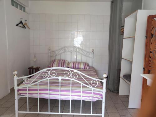 a bedroom with a white bed with purple stripes at Marilou in Basse-Terre