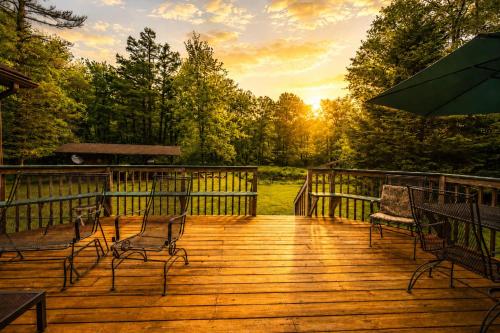 a wooden deck with chairs and an umbrella at Cozy Cabin w Pavilion Deck Fireplace & FirePit in Terra Alta