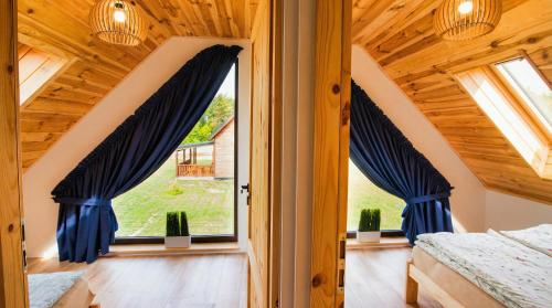 a bedroom with blue curtains and a window at Rumiane Chatki - Domki z Jacuzzi i Basenem in Rybno