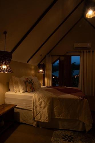 a bedroom with a large bed with a window at Quinta dos Laranjais Chalés in Viçosa do Ceará