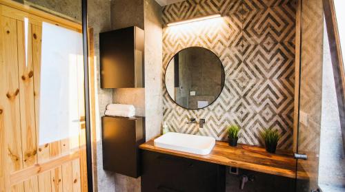 a bathroom with a sink and a mirror on a wall at Rumiane Chatki - Domki z Jacuzzi i Basenem in Rybno