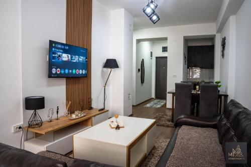 a living room with a couch and a tv on a wall at М Apartments Shtip in Štip