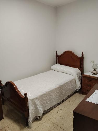 a bedroom with a bed with white sheets and a table at O Recuncho da Xunqueira in Viveiro