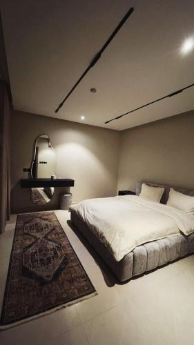 a bedroom with a large white bed and a rug at شاليه لوسيندا 2 in Baljurashi