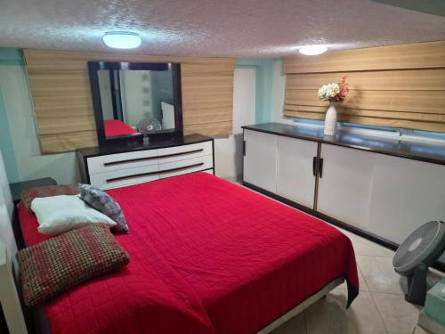 a bedroom with a red bed and a flat screen tv at Cocoyoc Residential Estate in Texcalpan