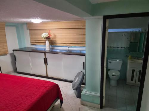 a bedroom with a red bed and a toilet at Cocoyoc Residential Estate in Texcalpan