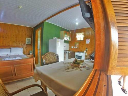 um quarto com uma mesa e uma cama e uma cozinha em Chalés Rincão Comprido em Canela