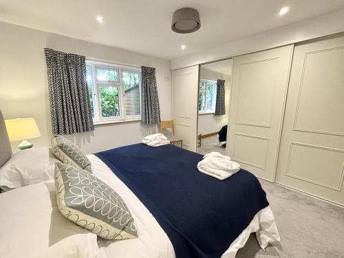 a bedroom with a large bed with blue sheets and pillows at Wyndthorpe Cottage in Milton Abbas