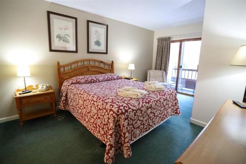 a hotel room with a bed with a red bedspread at Deer Park Condo 165D Vacation Rental near Loon Mountain in Woodstock
