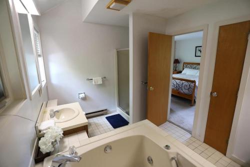 a bathroom with a tub and a sink and a bedroom at Forest Rim I1 WV Pet Friendly Ski Vacation Condo in Waterville Valley in Waterville Valley