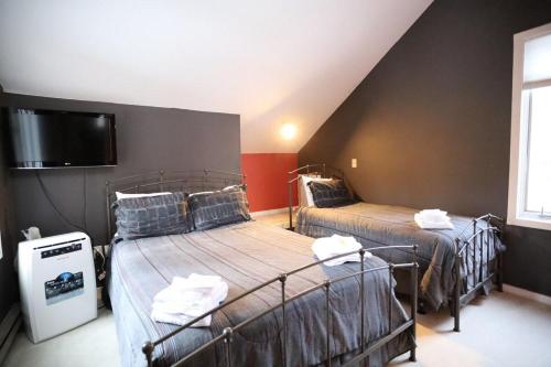 a room with two beds and a flat screen tv at Forest Rim I1 WV Pet Friendly Ski Vacation Condo in Waterville Valley in Waterville Valley