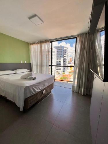 a bedroom with a bed and a large window at Solon Flat Manaira in João Pessoa