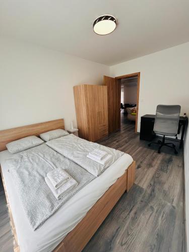 a bedroom with a large bed and a chair at iHome Apartman 4 in Pécs