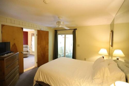a bedroom with a white bed and a television at Inns of Waterville Valley 105 One Bedroom Garden Level Unit at Inns of WV in Waterville Valley