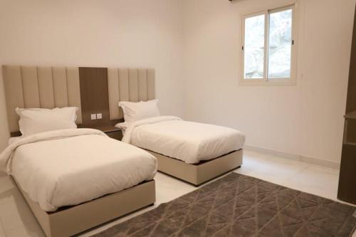 a bedroom with two beds and a window at شاليهات تايم in Khamis Mushayt