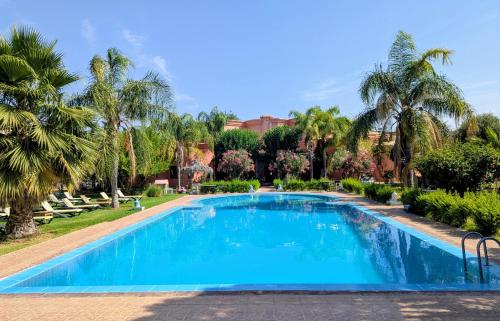 a swimming pool in a resort with palm trees at Las Palmeras Guest House in Marrakesh