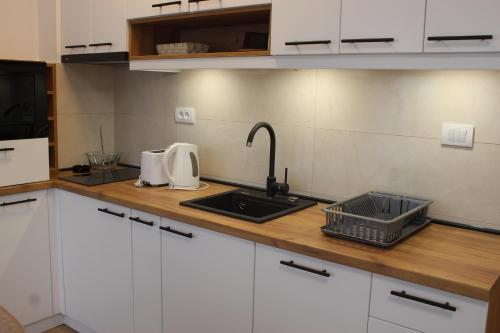 a kitchen with white cabinets and a sink and a counter at Apartmani Fontana Banja Koviljaca in Banja Koviljača